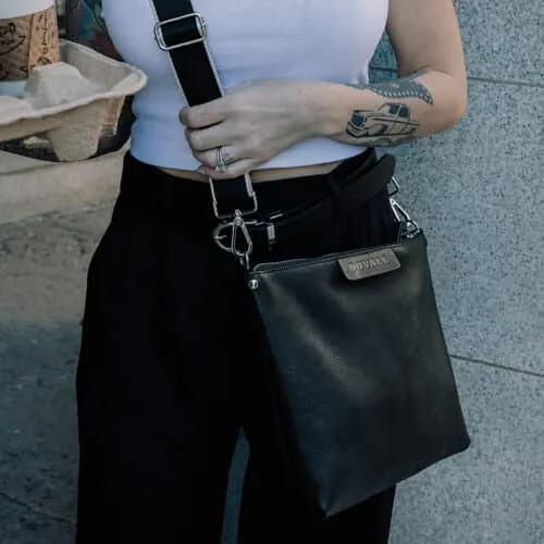 Woman wearing a black leather crossbody bag with a black nylon strap.