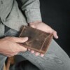 Man holding manmade vintage brown passport wallet