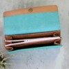 A vibrant women's turquoise leather wallet with beige interior and a white zipper enclosure