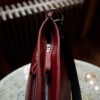 A red and black woman's purse is shown from the top to reveal zipper and strap grommet detail