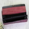 A deep purple wallet with black trim shown open to reveal black interior and zipper detail