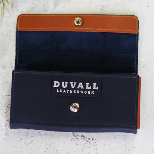 A deep blue leather wallet for women shown open to reveal orange trim and the Duvall logo