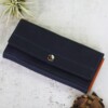 Women's deep blue leather wallet with orange folds shown closed with the silver button snap fastened