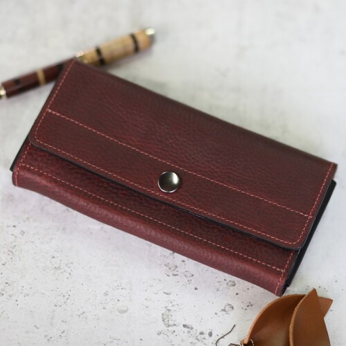 A rich red leather women's wallet shown closed with the snap fastened