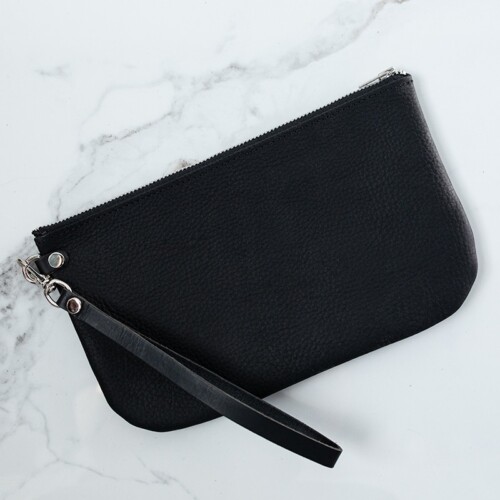 Back of black leather wristlet on white marble counter.