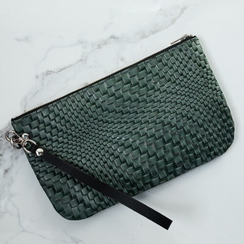 Back of green woven textured leather wristlet on a white marble counter.