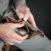 man taking outl money from second compartment of trifold wallet