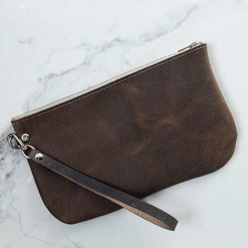 Back of a gray leather wristlet on a white marble counter