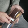 man pulling out card from bifold wallet in vintage brown leather made in USA