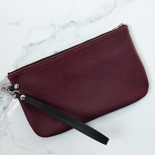Back of sangria purple leather wristlet on a white marble counter.