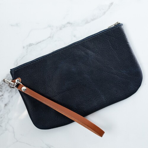 Back of a navy blue leather wristlet on a white marble counter