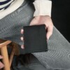 man with sweater hold a black bifold wallet that has ID window