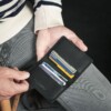 man holding blacket wallet that holds credit cards