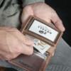 man taking out money from credit card wallet made with vintage brown leather