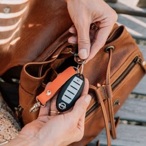 model clipping keys to hook inside of brown leather backpack purse