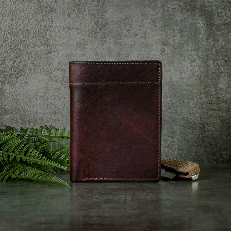 Dark mahogany passport wallet handmade in America with fine stitching with greenery and pocket knife.