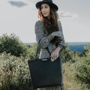 Women in field with genuine black leather tote bag