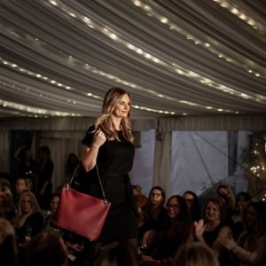 Model walking the Duvall Leatherwork runway with crimson red slouchbag