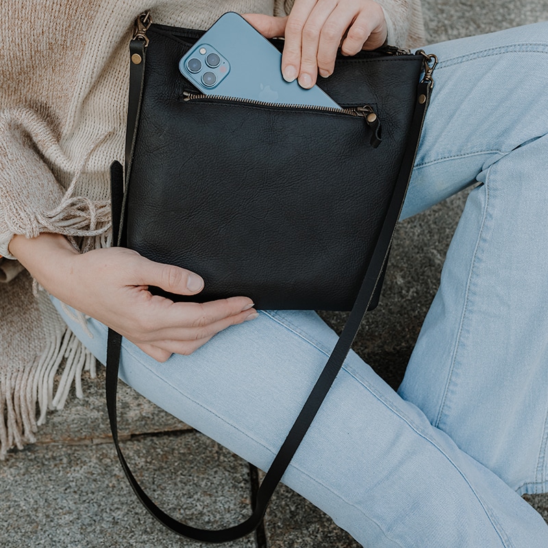 Woman pulling her phone from outside pocket of crossbody bag