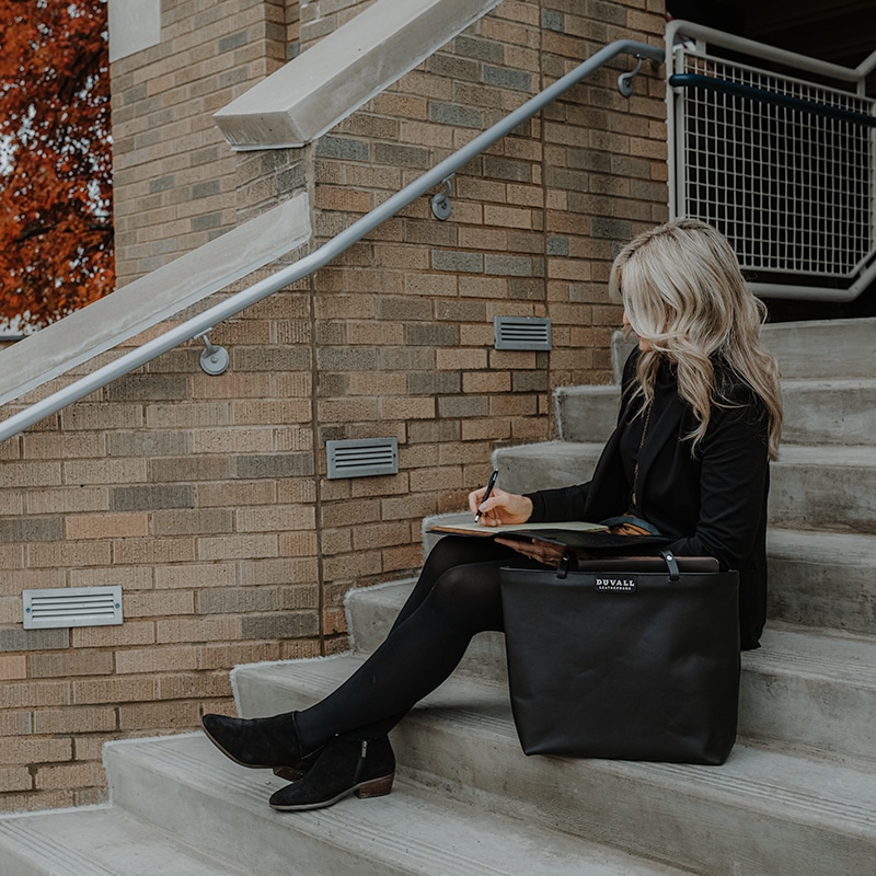 Business women on steps with black tote bag and padfolio