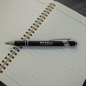 Black Duvall Leatherwork pen on top of an open lined notebook.