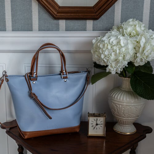 The blue handbag with brown accents and silver hardware is perfect for spring