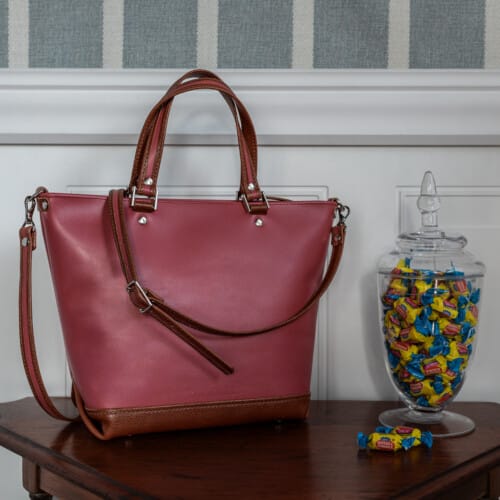 pink and brown leather purse with crossbody strap and carry handle