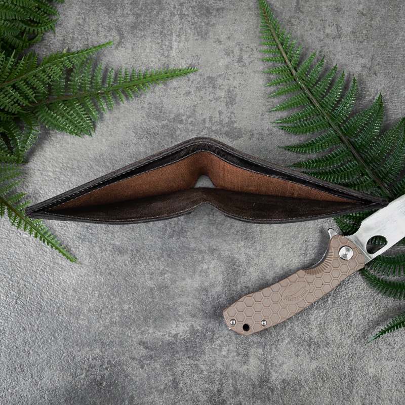 Cash pocket of bifold wallet that will hold your savings on a tabletop with greenery and pocket knife.