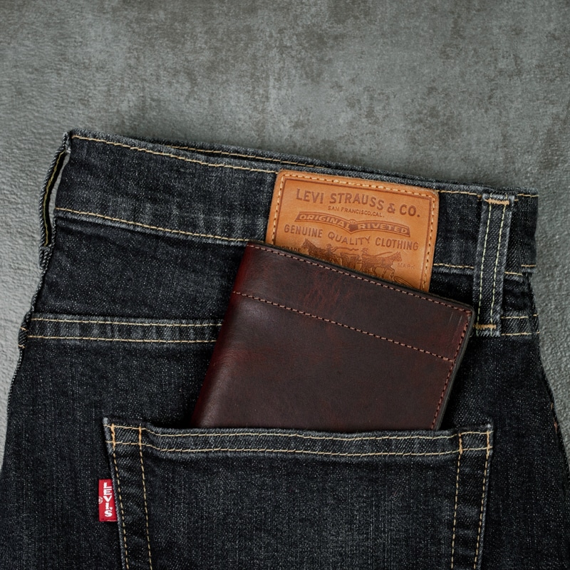 Passport wallet that fits in your back pocket shown here in jeans on a grey slate tabletop.