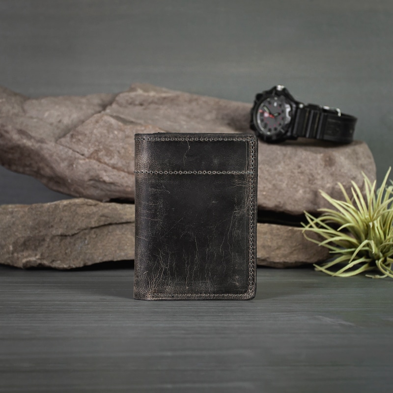 Anthracite Trifold wallet made with real leather with fine stitching is photographed with an outdoor setting in studio.
