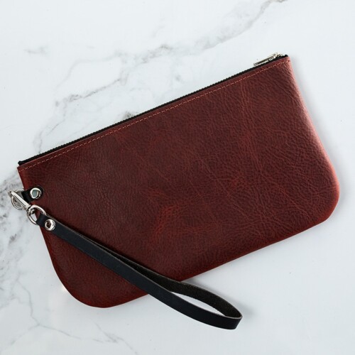 Back of red leather wristlet on a white marble counter.