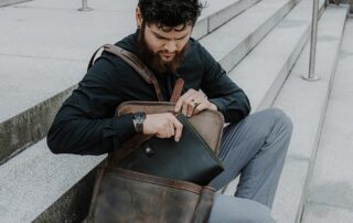 man pulling padfolio out of messenger bag
