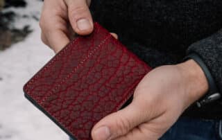 Red, Textured Bison Bifold Wallet being held in a man's hands to show the folded exterior cover of the wallet.