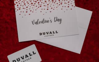 Photo of a white Duvall Leather gift card and Valentine's Day card with hearts on a red velvet backdrop