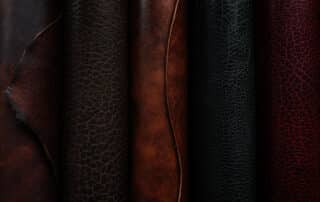 Five rolls of textured bison leather in different colors: dark mahogany, chocolate brown, bison brown, black, and red (sequoia)