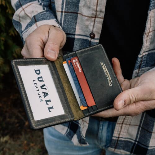 A man holding a small green bison leather wallet with 3 credit card slots and an ID holder.