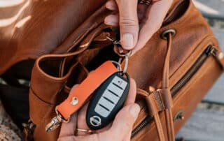 Lady holding a leather key fob attached to a leather bag.