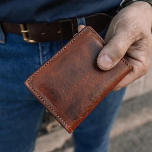 Man holding a brown bison leather minimalist wallet in his hand.